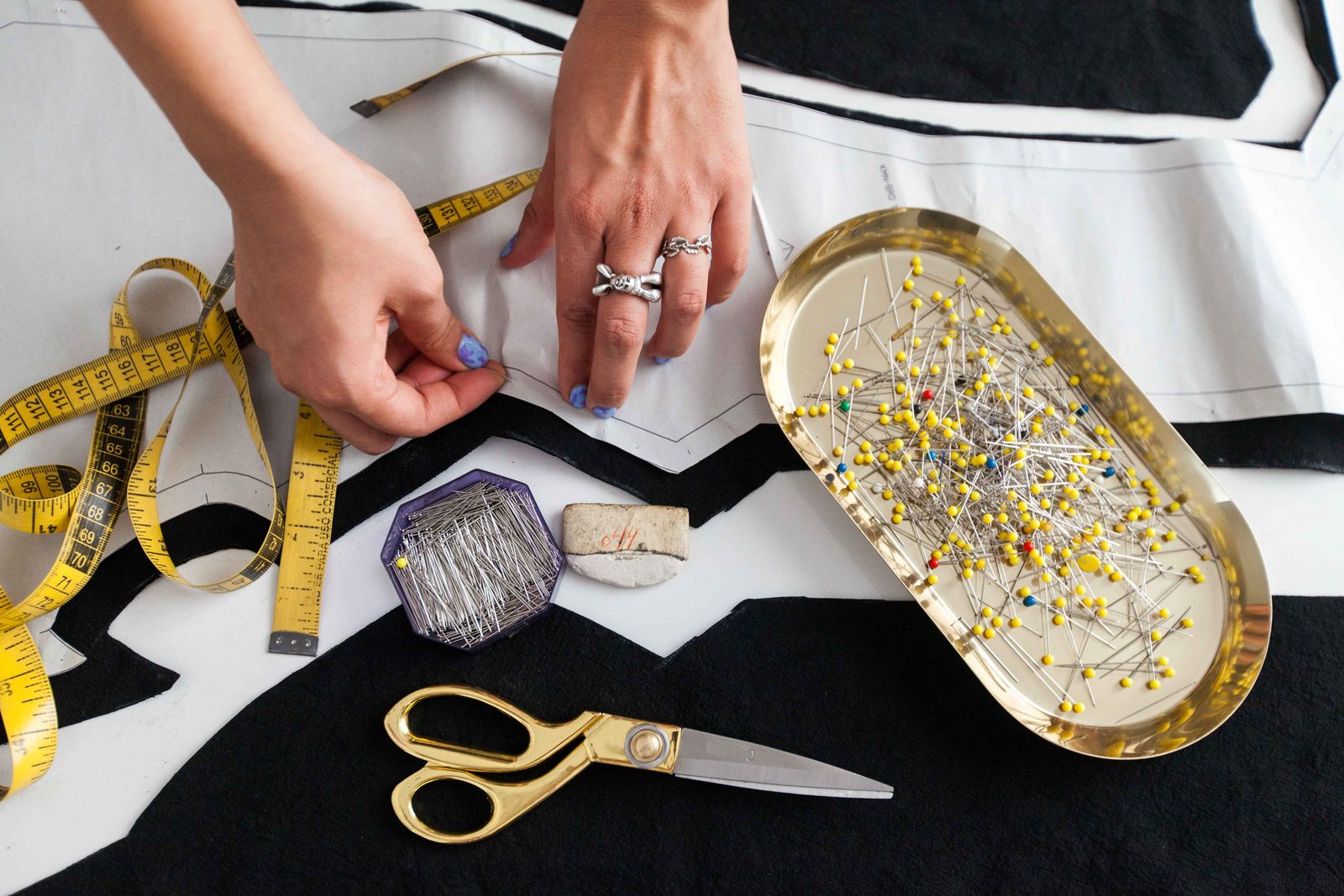 Hands pinning paper pattern pieces to cloth — reference photograph